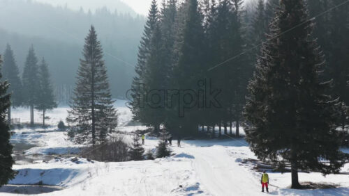 Panoramic aerial drone view of hikers walking in winter season with fir trees full of snow. Transylvania, Mount Ciucas in Romania, Carpathian mountains
