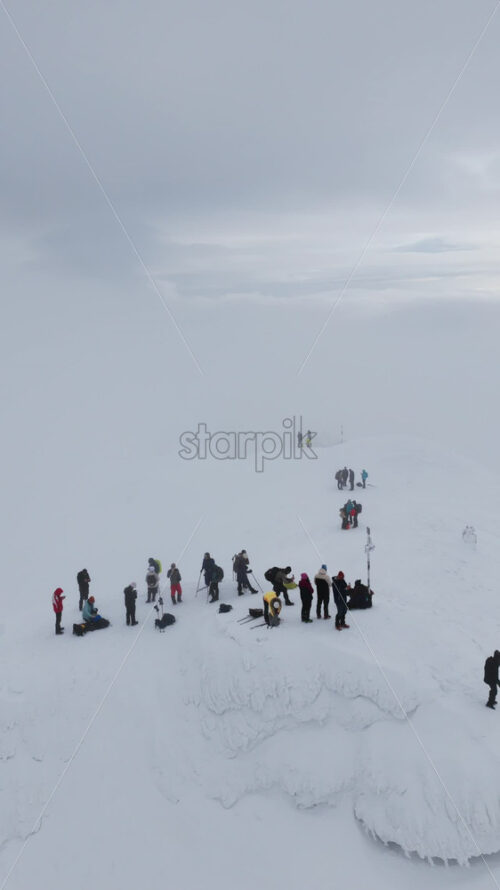 Aerial drone view of people hiking on Ciucas peak covered in snow in winter season. Romania, Carpathian Mountains