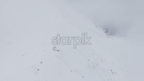 Aerial drone view of people hiking on Ciucas peak covered in snow in winter season. Romania, Carpathian Mountains