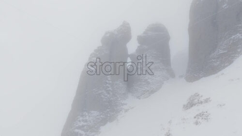 Aerial drone view of Babele la Sfat (Old Ladies's Council) rock formation covered in snow in winter season. Romania, Carpathian Mountains