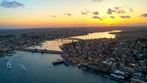 Aerial drone view of Istanbul at sunset, Turkey. Multiple residential buildings, mosques, Galata and Metro bridges over the Golden Horn waterway with floating ships - Starpik Stock