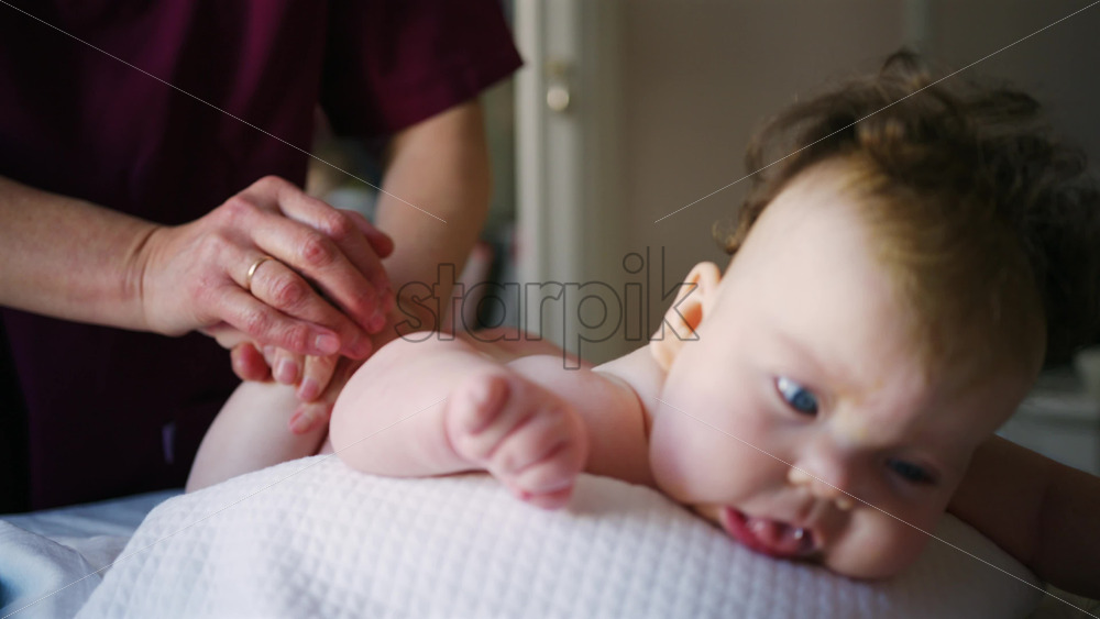Caregiver doing mobility exercises with a baby - Starpik Stock