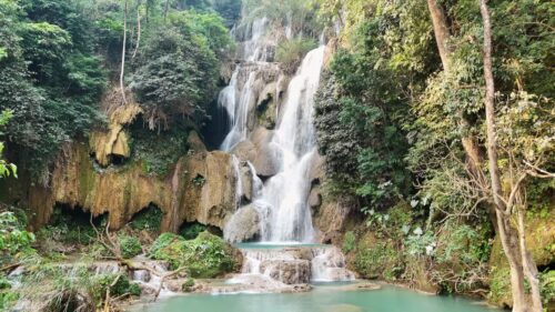 Video – Aerial drone view of Kuang Si Waterfall main cascade near Luang Prabang, where multiple streams of water fall down limestone rock formations into turquoise pools surrounded by dense jungle - Starpik Stock