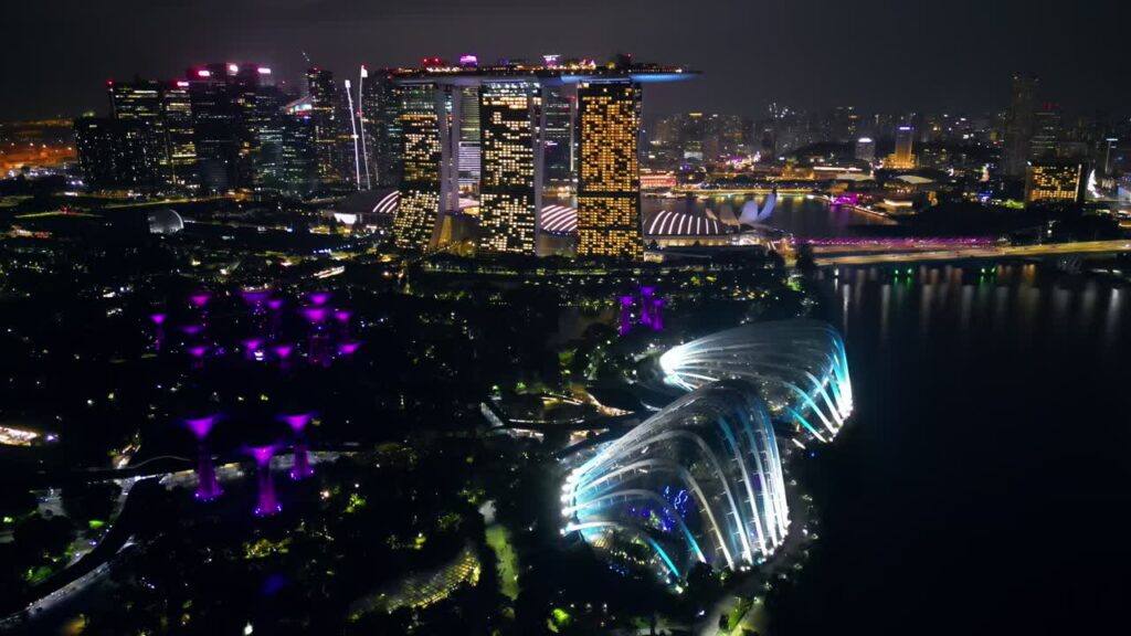 Video – Aerial drone view of Marina Bay in Singapore at night showing Marina Bay Sands, the Singapore Flyer observation wheel, and illuminated waterfront skyline - Starpik Stock