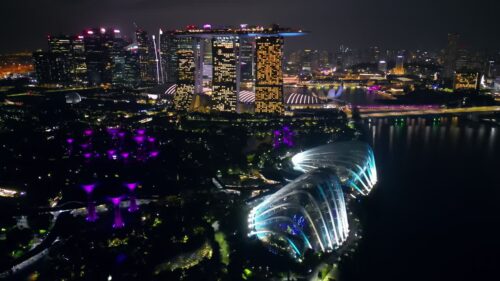 Video – Aerial drone view of Marina Bay in Singapore at night showing Marina Bay Sands, the Singapore Flyer observation wheel, and illuminated waterfront skyline - Starpik Stock