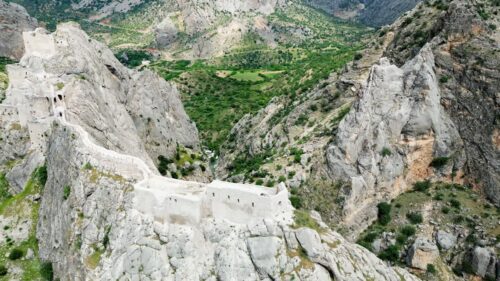 Video – Aerial drone view of a historic fortress built along dramatic mountain cliffs overlooking a canyon valley, highlighting ancient architecture and landscapes of the Mesopotamia region - Starpik Stock