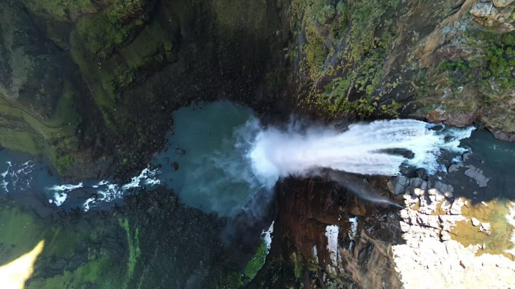 Video – Aerial drone view of water cascading over the edge of Maletsunyane Falls into the river far below, showing the powerful waterfall and surrounding canyon landscape - Starpik Stock