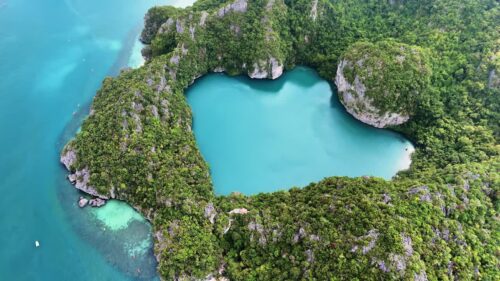 Video – Aerial drone view of waves crashing against rocky coastline and turquoise water along a tropical beach in Thailand - Starpik Stock