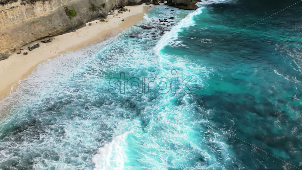 Video - Aerial drone view of Diamond Beach and its iconic offshore rock pinnacle in Nusa Penida, Bali. Powerful ocean waves meet dramatic limestone cliffs and lush tropical vegetation