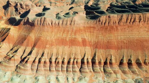 Video - Aerial drone view of layered sandstone cliff formations in Zhangye Danxia Geopark, Gansu Province, China