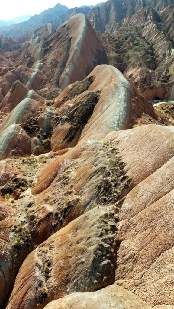 Video - Aerial drone view of the colorful layered rock formations of Zhangye Danxia National Geopark in Gansu Province. Vertical