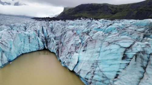 Video - Aerial drone view of Svartifoss waterfall in Skaftafell, Vatnajokull National Park, Iceland. The waterfall plunges into a small pool surrounded by dramatic black basalt column cliffs