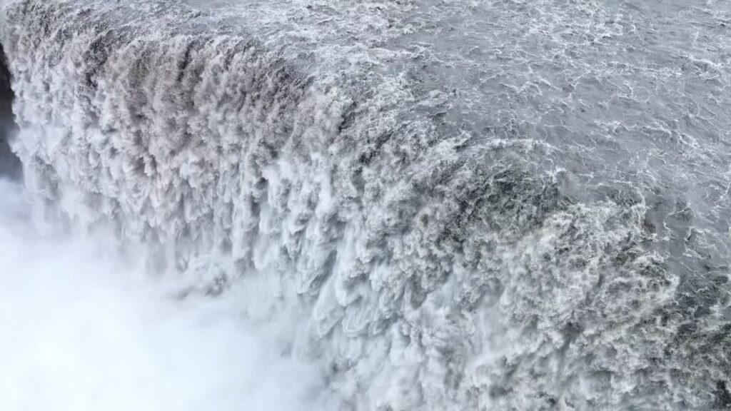 Video - Aerial drone view of Dettifoss waterfall in Vatnajokull National Park, Northeast Iceland. Europe's most powerful waterfall crashes into a mist filled canyon with roaring white water and dramatic volcanic rock cliffs