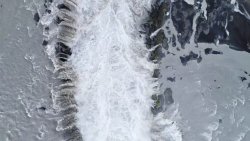 Video - Aerial drone view of the immense curtain of water at Dettifoss waterfall. Turbulent whitewater surges over the cliff edge into a mist filled canyon