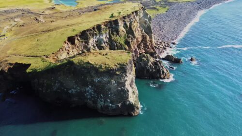 Video - Aerial drone view of dramatic sea cliffs rising above the North Atlantic Ocean. Steep volcanic rock formations drop into deep blue water along Iceland's rugged coastline
