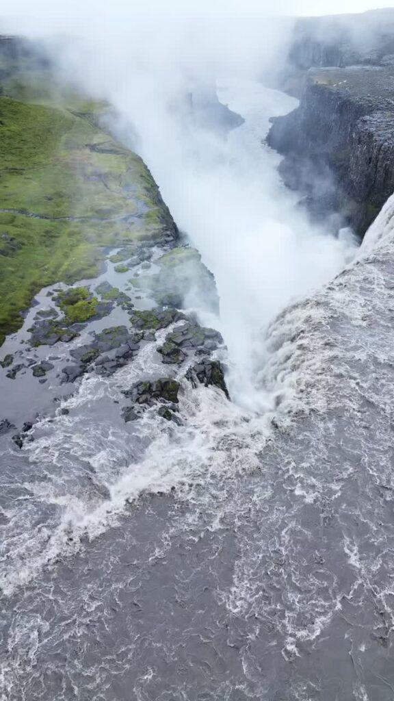 Video - Aerial drone view above Gullfoss waterfall as powerful glacial water plunges into a deep canyon. Mist rises dramatically from the cascading falls in southwest Iceland. Vertical