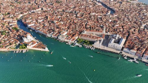 Video - Aerial drone view of Venice showing St. Mark's Square, the Campanile, Doge's Palace, and Santa Maria della Salute across the Grand Canal. Boats and water taxis navigate the lagoon