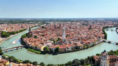 Video - Aerial drone view of Verona Cathedral and the dense historic center with terracotta rooftops along the Adige River in northern Italy.