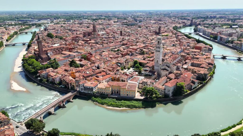Video - Aerial drone view of Verona Cathedral and the dense historic center with terracotta rooftops along the Adige River in northern Italy.