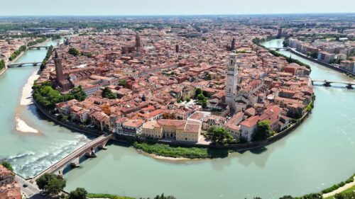 Video - Aerial drone view of Verona Cathedral and the dense historic center with terracotta rooftops along the Adige River in northern Italy.