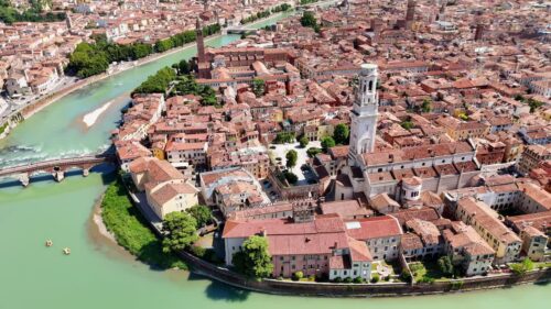 Video - Aerial drone view of Verona Cathedral and the dense historic center with terracotta rooftops along the Adige River in northern Italy.