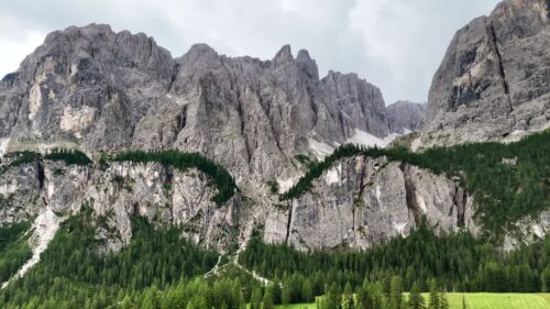 Video - Aerial drone view of steep limestone cliffs and alpine forest in the Dolomites. The rugged mountain range creates a dramatic natural landscape in northern Italy