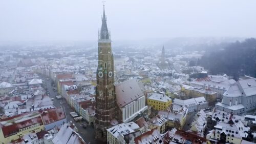 Video - Aerial drone view over snow covered Landshut city center, highlighting the towering Gothic spire of St. Martin's Church, one of the tallest brick churches in the world