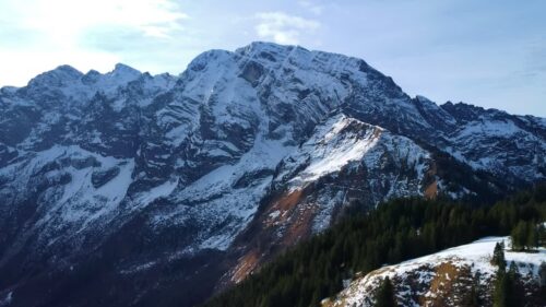 Video - Aerial drone view of rugged snow covered mountains in the Bavarian Alps, with forested slopes and dramatic alpine ridges under cold winter light