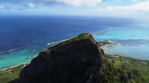 Video - Aerial drone view past Le Morne Brabant mountain in Mauritius, overlooking the turquoise lagoon and coral reefs of the Indian Ocean