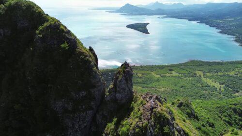 Video - Aerial drone view of rugged mountain peaks overlooking a wide valley landscape in Lesotho with distant mountains and blue sky