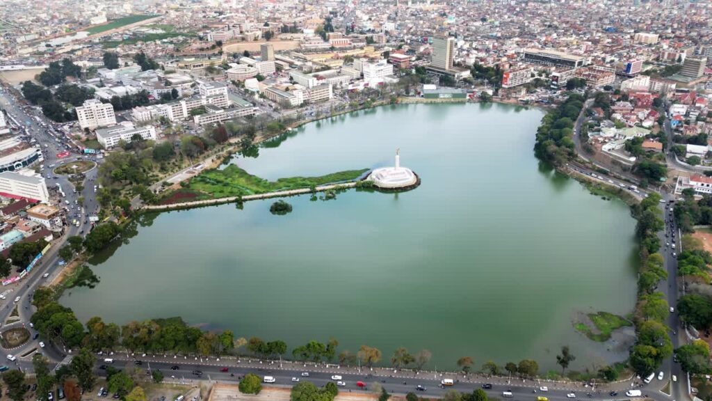Video - Aerial drone view of Lake Anosy with the central monument island and surrounding city of Antananarivo, showing the urban landscape of Madagascar's capital from above