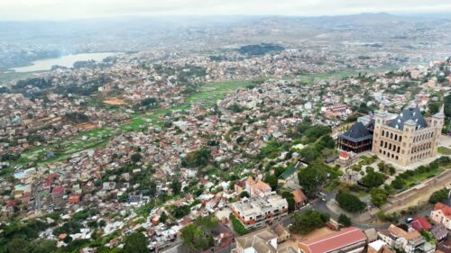 Video - Aerial drone view of Antananarivo cityscape with the Rova of Antananarivo on the hilltop, surrounded by residential neighborhoods and green rice fields in the distance