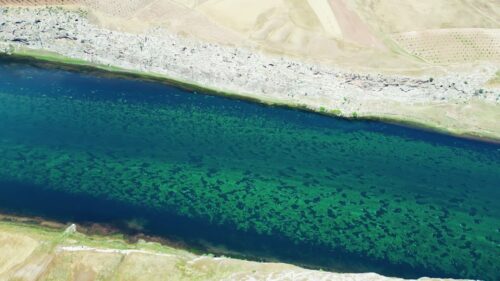 Video - Aerial drone view of the Tigris River winding through agricultural fields and cliffs in the Mesopotamia region of southeastern Turkey, showing fertile farmland and dramatic river landscapes