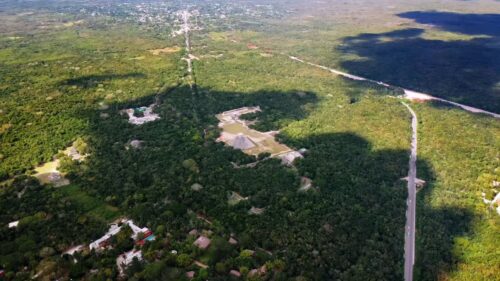 Video - Aerial drone view of an ancient Mayan pyramid surrounded by dense tropical jungle in Mexico, showing the impressive archaeological site rising above the forest