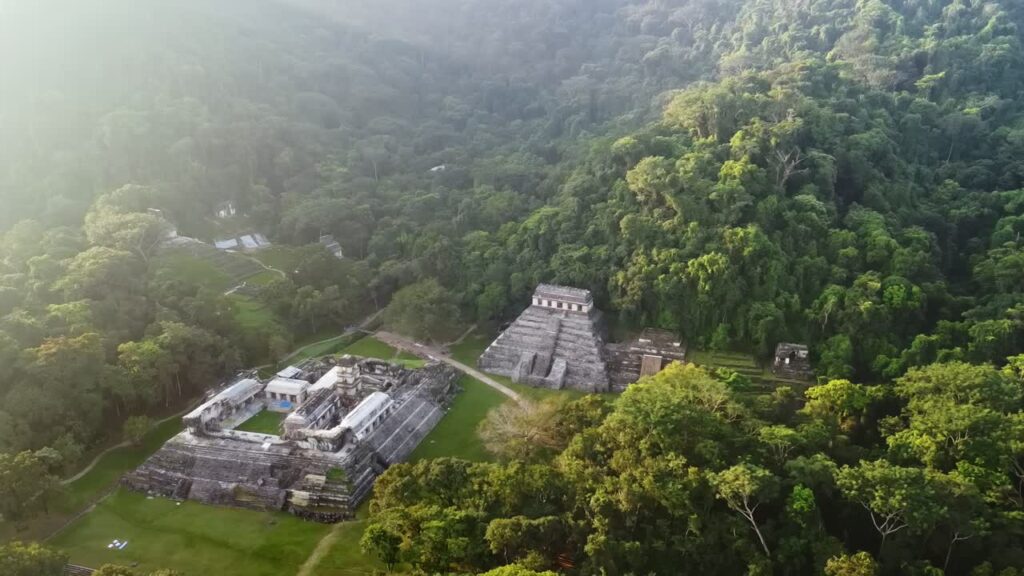 Video - Aerial drone view of Palenque Mayan ruins featuring ancient pyramids and temples surrounded by tropical jungle in southern Mexico