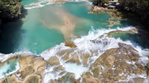Video - Aerial drone view multiple turquoise waterfalls and natural pools surrounded by dense tropical forest at Agua Azul in southern Mexico