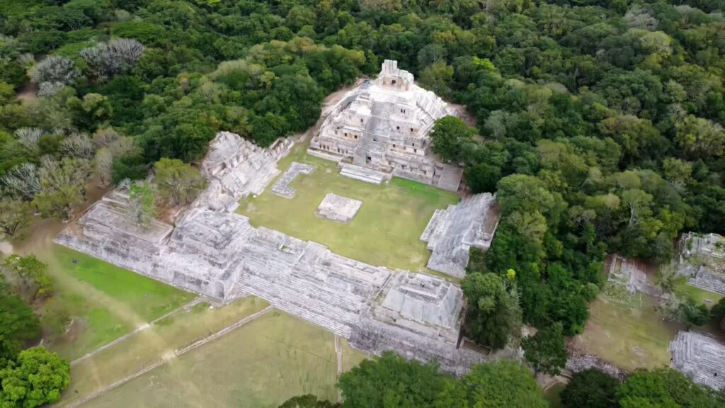 Video - Aerial drone view revealing a historic Mayan temple complex surrounded by lush jungle vegetation in Mexico