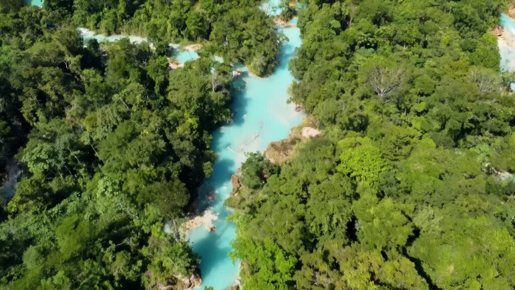 Video - Aerial drone view of Agua Azul's layered waterfalls and natural turquoise pools formed by mineral deposits in the Chiapas jungle
