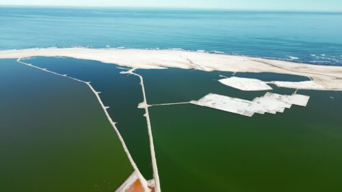 Video - Aerial drone view of coastal salt evaporation ponds near the Atlantic Ocean in Namibia with geometric patterns of salt fields and green water basins