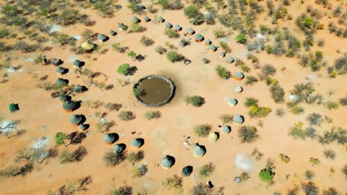 Video - Aerial drone view of a traditional circular Himba village settlement in northern Namibia with huts arranged around a central livestock enclosure