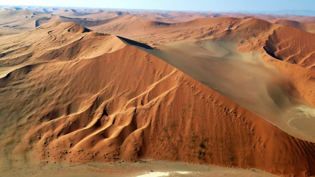 Video - Aerial drone view of endless sand dunes stretching across the Namib Desert creating dramatic patterns and textures