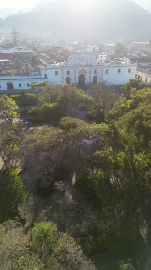 Video - Aerial drone view above trees revealing Antigua Cathedral and the historic colonial city center. Vertical