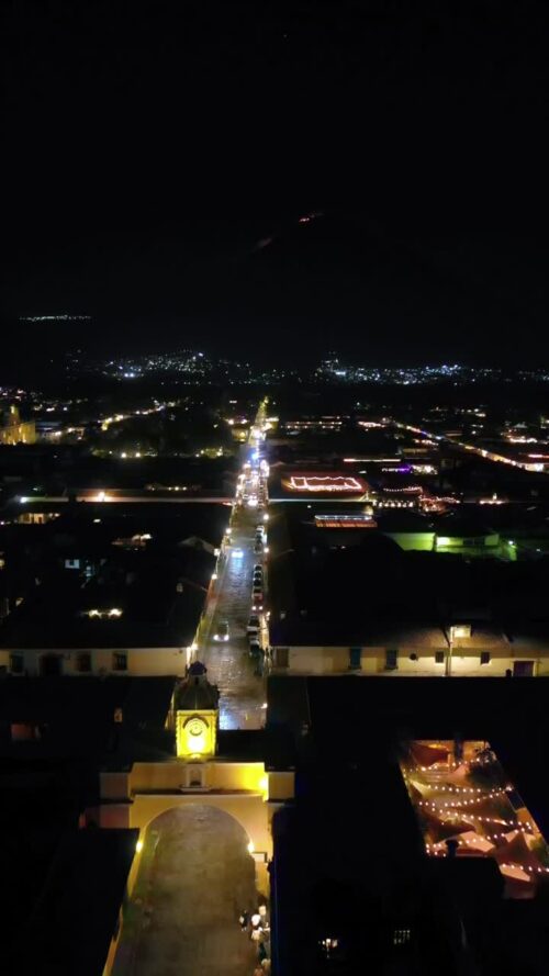Video - Aerial drone view of the iconic Santa Catalina Arch and illuminated colonial street in Antigua Guatemala at night
