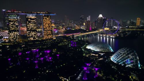 Video - Aerial drone view of Marina Bay in Singapore at night showing Marina Bay Sands, the Singapore Flyer observation wheel, and illuminated waterfront skyline