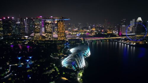 Video - Aerial drone view of Marina Bay in Singapore at night showing Marina Bay Sands, the Singapore Flyer observation wheel, and illuminated waterfront skyline