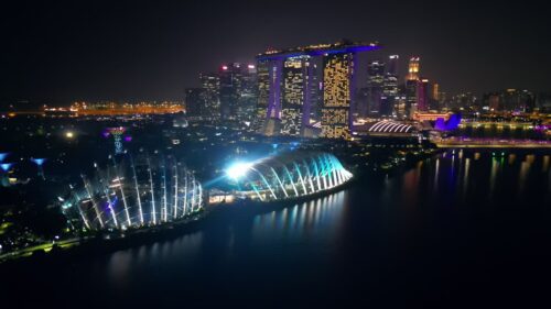 Video - Aerial drone view of Singapore's Marina Bay skyline at night featuring Marina Bay Sands, the ArtScience Museum, and illuminated bridges
