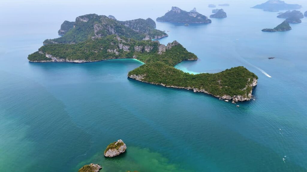 Video - Aerial drone view of tropical islands and turquoise water in southern Thailand with limestone formations and small boats in the Andaman Sea