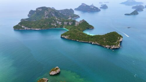 Video - Aerial drone view of tropical islands and turquoise water in southern Thailand with limestone formations and small boats in the Andaman Sea