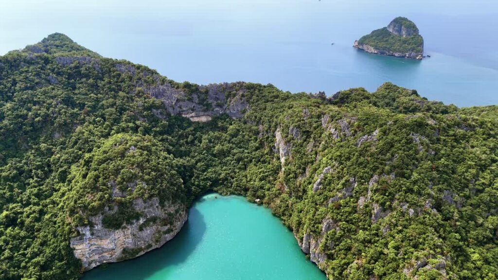 Video - Aerial drone view of a hidden lagoon surrounded by limestone cliffs and jungle vegetation in Thailand