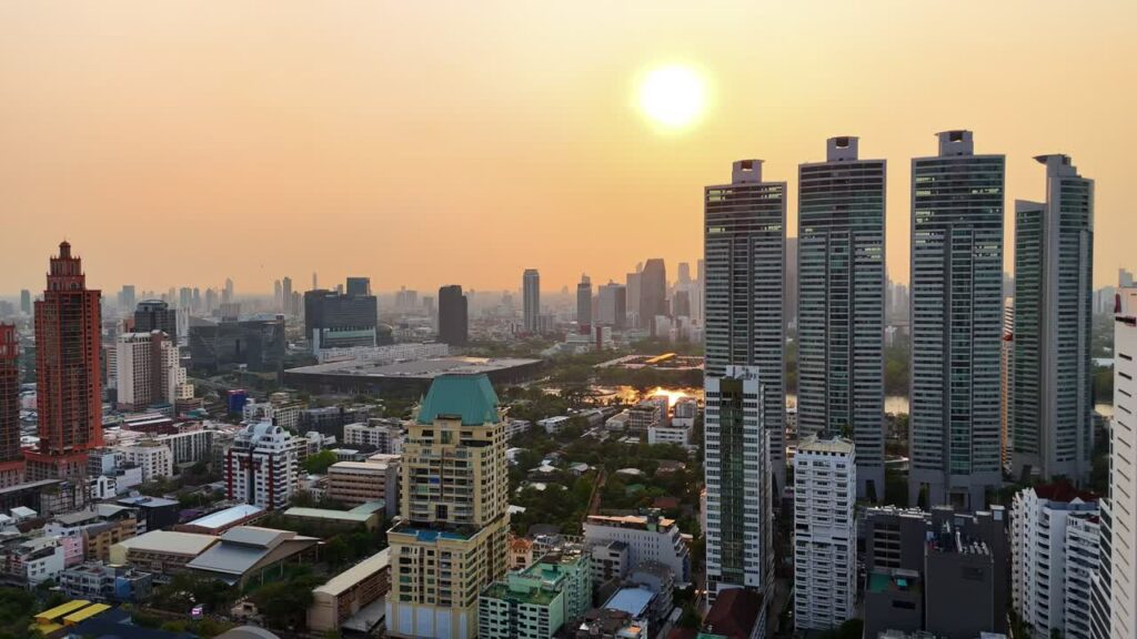 Video - Aerial drone view of Bangkok skyline at sunset with modern high rise buildings and golden evening light